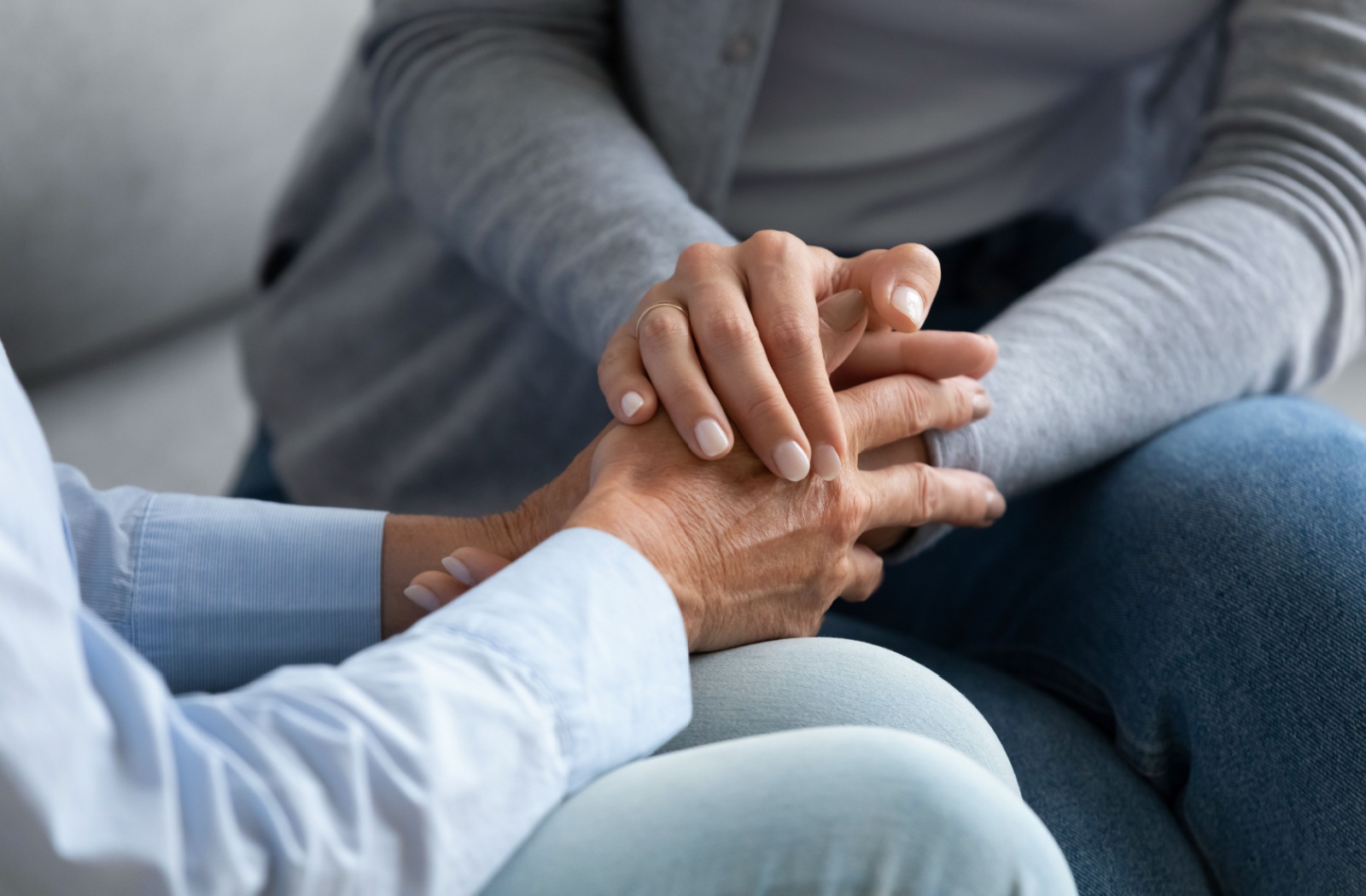 A close up of an adult woman holding hands with an older woman
