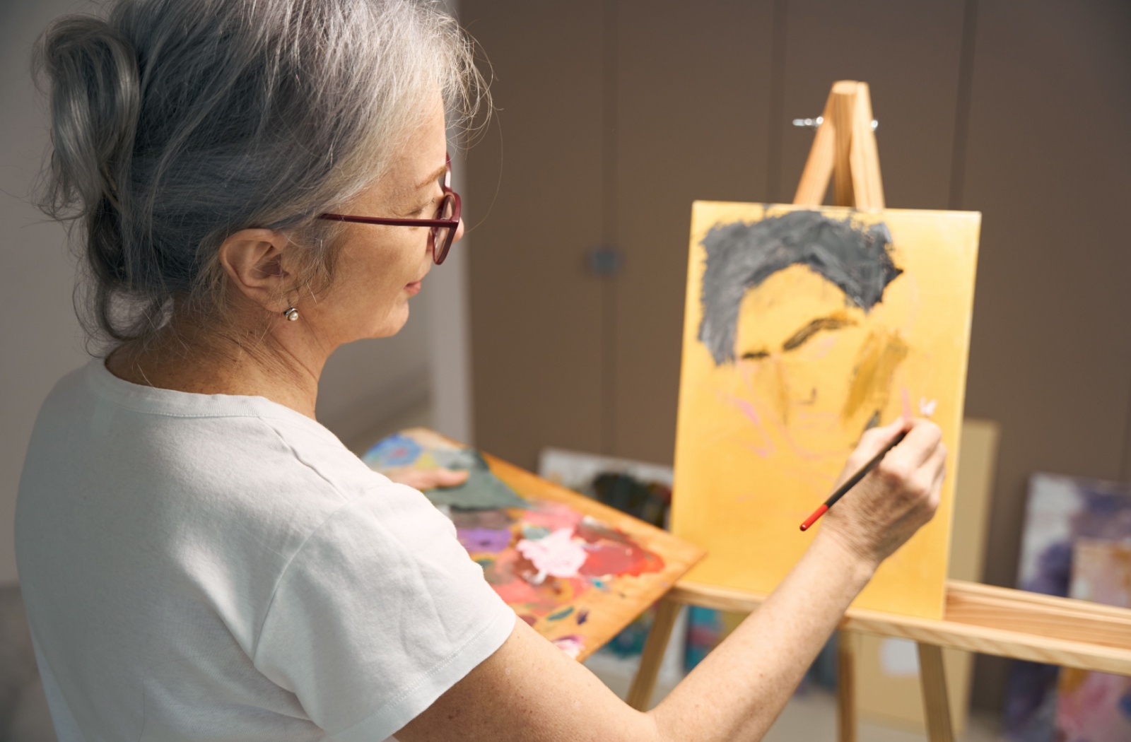 An older adult happily uses a paint set gifted by their family.